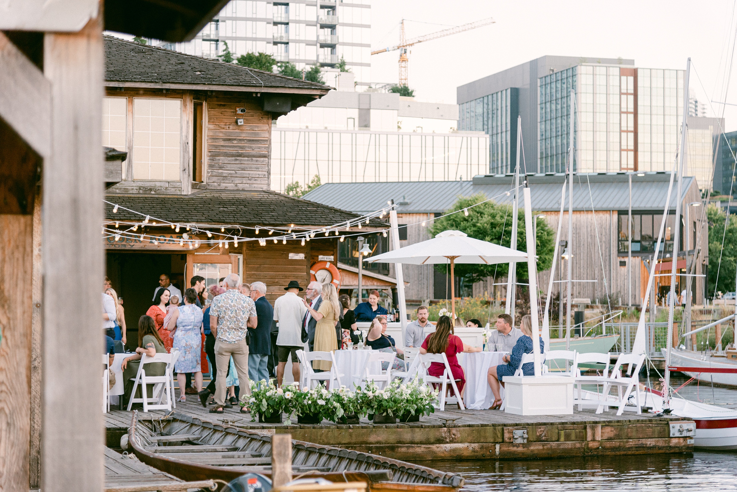 Fine Art Weddings in Seattle Washington. The Center for Wooden Boats, the photo is from the dock facing the venue and the guests having fun. The cityscape is in the background.