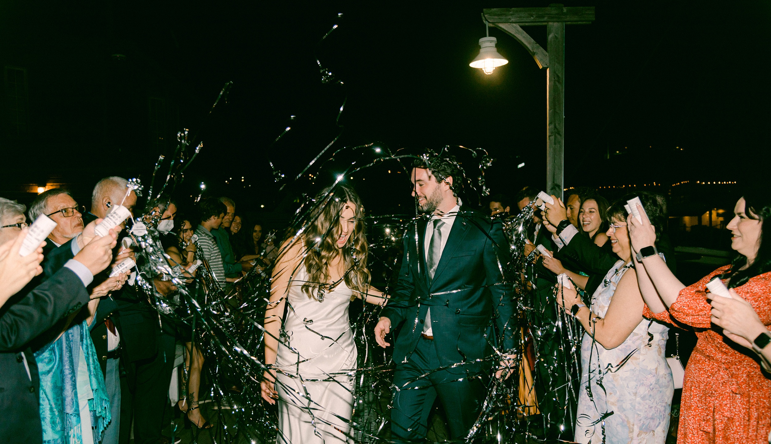 Fine Art Weddings in Seattle Washington. The Center for Wooden Boats, Bride and Groom at their wedding exit, walking through their guests who have confetti streams popping across the image.
